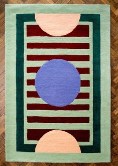 an area rug with circles and stripes on the floor in front of a wooden floor