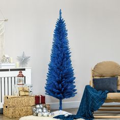 a blue christmas tree in a living room next to a chair and other holiday decorations