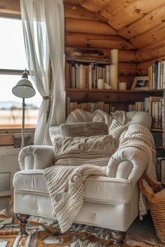 a living room filled with furniture and bookshelves next to a window covered in white curtains