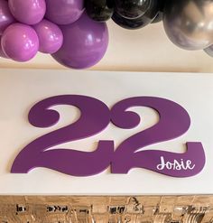 purple and black balloons are hanging above the sign that reads, 22 jolie's