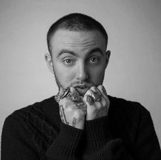 a black and white photo of a man holding his hands to his mouth while looking at the camera