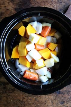 a bowl filled with diced vegetables on top of a wooden table