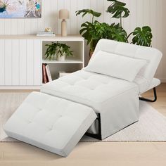 a white reclining chair sitting on top of a rug next to a potted plant