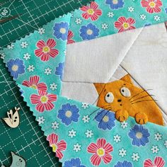 an envelope with a cat sticking out of it's side on top of flowers