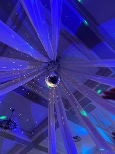 the ceiling is decorated with blue lights and white draping, while someone holds their hand up to take a photo