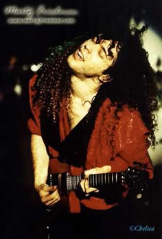 a man with long hair holding a guitar in his right hand and looking up at the sky