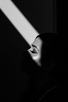 black and white photo of woman's face with light coming through the window behind her