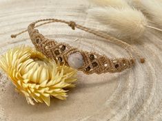 a yellow flower sitting on top of a sandy ground next to a feather and beaded headband