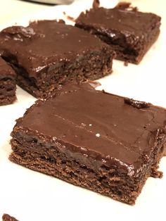 several pieces of chocolate cake sitting on top of a white countertop next to each other