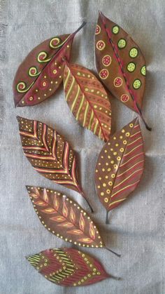 four different colored leaves are arranged on a gray tablecloth, one is red and the other is green