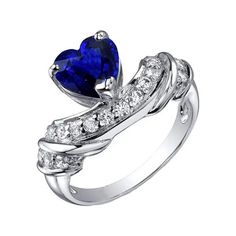 a heart shaped blue sapphire and diamond ring with white diamonds on the band, set in 18k white gold