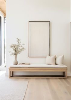 a living room with white walls and wooden flooring next to a large painting on the wall