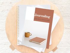 a table with two books and a cup on it next to a pair of coffee mugs