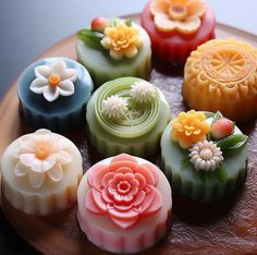 there are many soaps on the wooden tray with flowers in them and one is made out of fondant