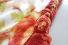 a close up view of a red and yellow object on a white tablecloth with flowers