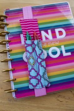 a colorful notebook with two pens sticking out of it's cover and the words nd new cool written on top