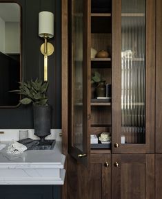 a bathroom sink sitting under a mirror next to a wooden cabinet with glass doors on it