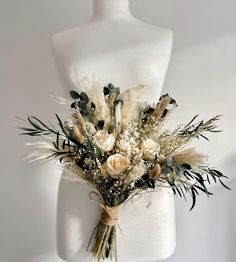 a white mannequin holding a bouquet of flowers and greenery on it's torso