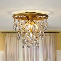 a golden chandelier hanging from the ceiling in a room with curtains and drapes