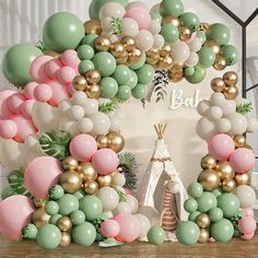 the balloon arch is decorated with pastel green, pink and gold balloons