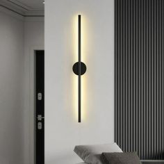 a black and white photo of a modern light fixture on the wall next to a bed