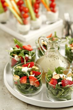 a plate topped with salad and cups filled with fruit