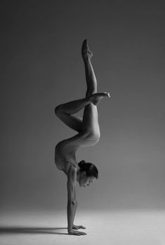 a woman is doing a handstand on one leg and her legs are bent forward