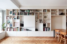 a dining room table with chairs and bookshelves