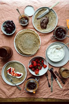 a table topped with lots of food and desserts on top of a pink cloth