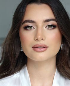 a woman with long hair wearing white shirt and earrings