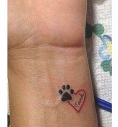 a small wrist tattoo with a heart and paw prints on it