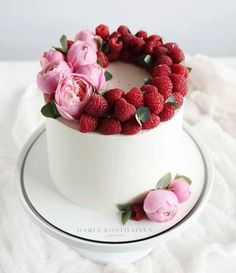 a white cake with raspberries and flowers on top