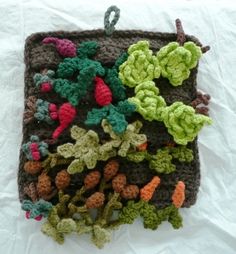 a crocheted pot holder with many different colored plants in it on a white surface