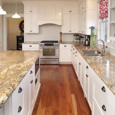 a large kitchen with white cabinets and marble counter tops, along with hardwood flooring