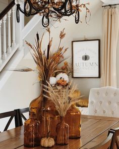 a wooden table topped with vases filled with flowers and plants next to a stair case