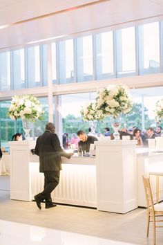 a man standing in front of a counter with flowers on it at a wedding reception