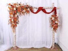 an arch decorated with flowers and branches for a wedding or reception ceremony in front of a white curtain