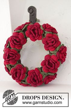 a crocheted wreath hanging on the side of a white wall with a hook