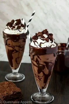 two glasses filled with chocolate milkshakes and topped with whipped cream