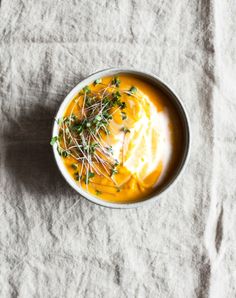 a white bowl filled with soup and garnished with parsley on the side