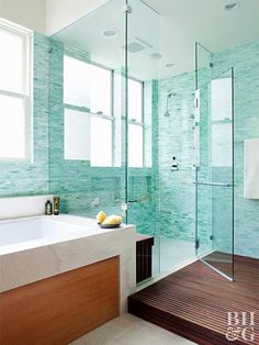 a modern bathroom with green tiles and wood flooring, along with a walk in shower