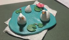 two white birds sitting on top of a blue plate with water lilies and lily pads