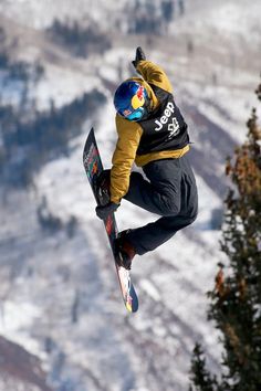 a man flying through the air while riding a snowboard on top of a mountain