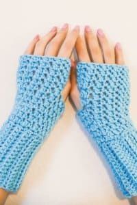 two hands with blue knitted gloves on top of each other