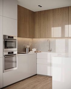 a kitchen with white cabinets and wood flooring is pictured in this image, there are two ovens on the counter