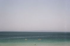 two people in the ocean with surfboards on their feet and one person standing out in the water