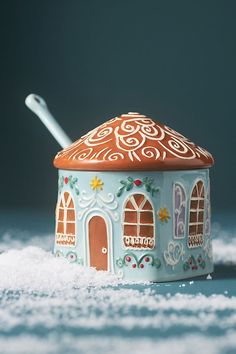 a ceramic container with a spoon in it sitting on some white snow covered ground next to a blue background