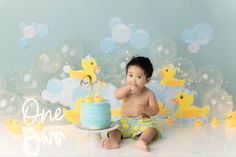 a baby boy sitting in front of a cake