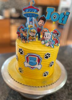 a yellow cake with paw patrol decorations on it