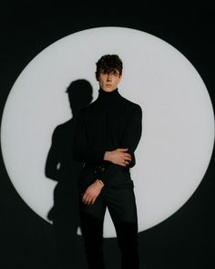 a man standing in front of a large white circle with his shadow on the wall